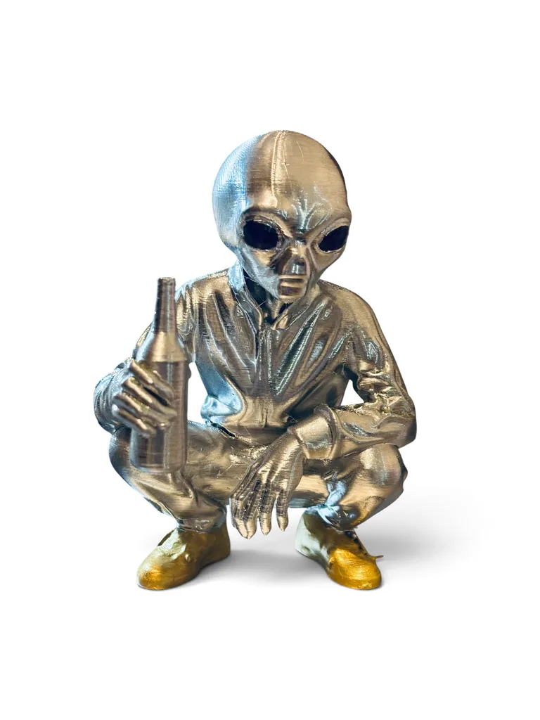 Escultura física de alien plateado con botella